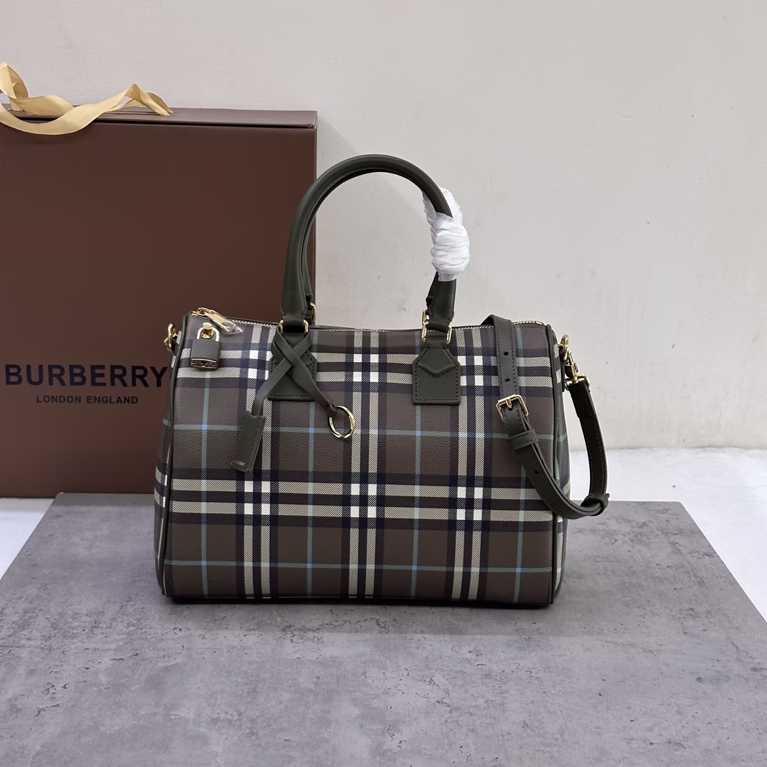 P1080 Burberry Medium Pillow Bag, stand-up design with Burberry check pattern, leather wrap padlock and luggage tag 30 x 15 x 21 cm. Leather top handle. Detachable and adjustable shoulder strap. Zipper closure. Hand-painted edges. Glossy metal hardware. Leather wrapped padlock. Luggage tag. Luggage tag with Burberry letter embossed logo.
