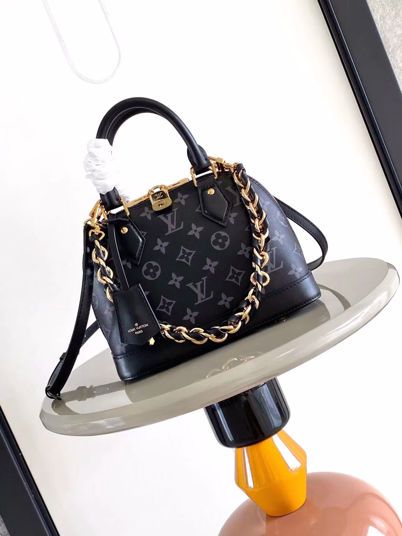M12289 M12561 The Monogram Ink collection presents the Alma BB bag, an elegant interpretation of the original 1934 design in cowhide leather covered in the brand's Monogram motif, with a new braided chain for an elegant finish. 23.5 x 17.5 x 11.5 cm (L x H x W).