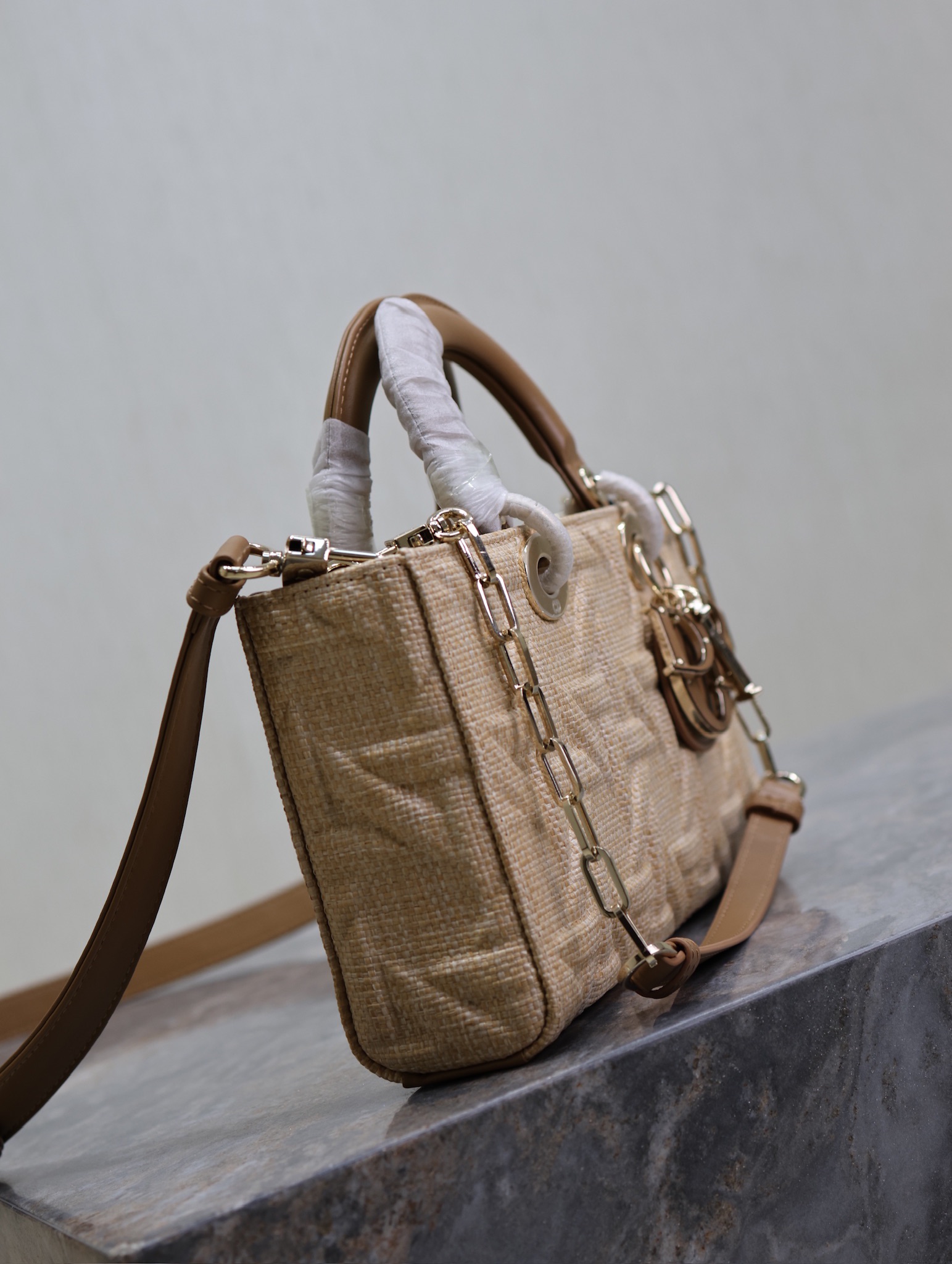 P1340 Medium Lady D-Joy Handbag "Raffia Rattan" This Lady D-Joy handbag highlights the minimalist aesthetic of the Lady Dior collection, which focuses on Dior's profound vision of elegance and beauty, crafted in beige raffia and decorated with a Graphic rattan check pattern in a sleek, 3D version of Dior's iconic motifs in camel leather. D.I.O.R. charm adds a touch of movement to the delicate silhouetteMedium size with detachable chain shoulder strap and adjustable, detachable leather shoulder strapCan be carried by hand, over the shoulder or across the bodyIdeal for everyday stylingDetachable chain shoulder strapAdjustable, detachable leather shoulder strapModel no.: 0613Dimensions: 26 x 13.5 x 5 cm (L x H x W)Holds 1 cell phone, 1 card holder, Sunglasses and Lipstick-High Fake Factory