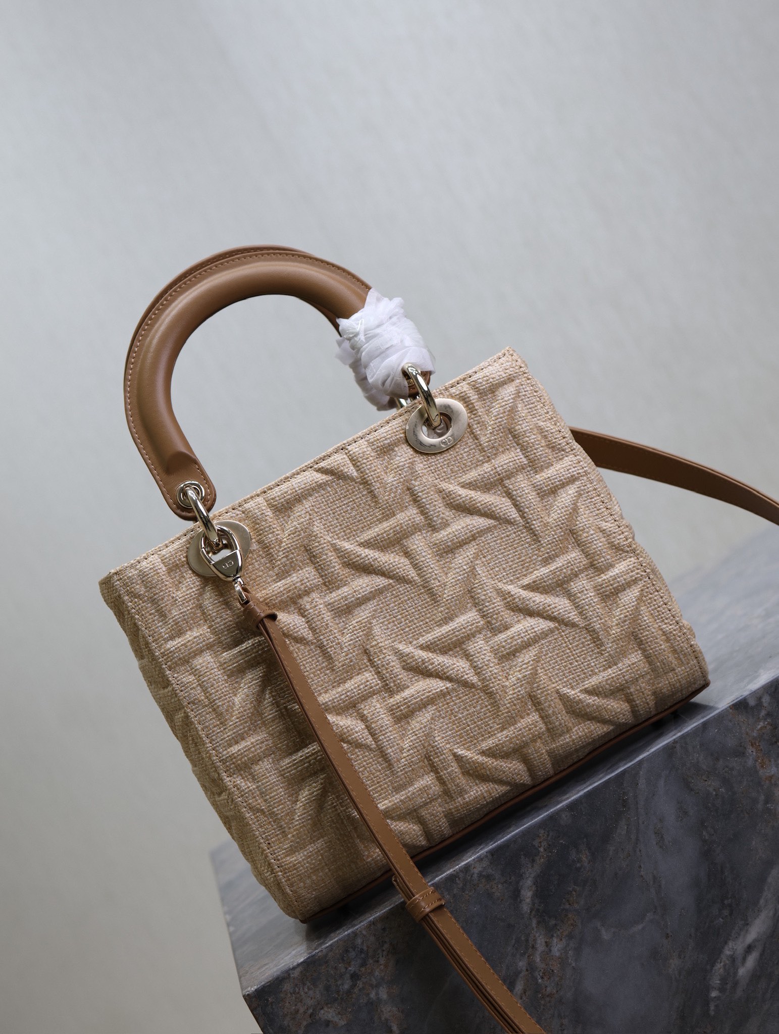 P1380 5-compartment Lady Dior bag "Raffia Rattan Check" This Lady Dior bag highlights the minimalist aesthetic of the Lady Dior collection and focuses on Dior's profound vision of elegance and beauty, crafted in beige raffia and adorned with a Graphic Rattan Check pattern, in a sleek 3D version of Dior's iconic motifs, with a camel leather D.I.O.R. charm that adds a touch of movement to the silhouette. I.O.R. charm adds a touch of movement to the delicate silhouetteMedium size with adjustable, detachable leather shoulder strapCan be carried by hand, over the shoulder or across the bodyIdeal for everyday stylingAdjustable, detachable leather shoulder strapModel No.: 0565Measurements: 24 x 20 x 11 cm (L x H x W)-High-Fashion Factory