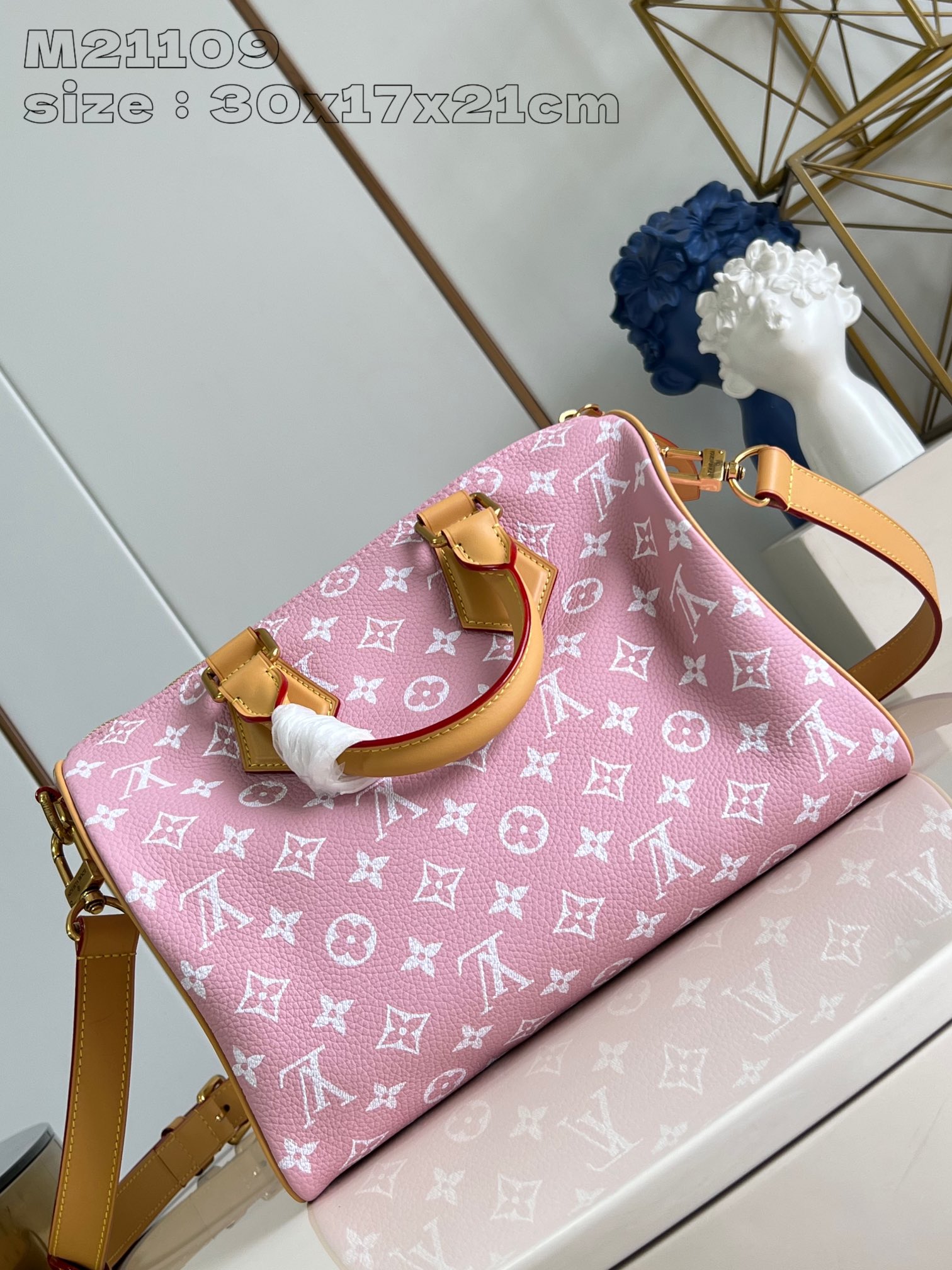 P2600 M21109 Pink Leather The Speedy P18 Bandoulière 30 Monogram Leather Handbag delivers an opulent texture in supple cowhide leather with a Monogram print that mirrors the Monogram elements on the canvas. Polished metal hardware, sheepskin leather lining and built-in tag highlight Creative Director Pharrell Williams' attention to detail. Dimensions: 30 x 17 x 21 cm (L x H x W)