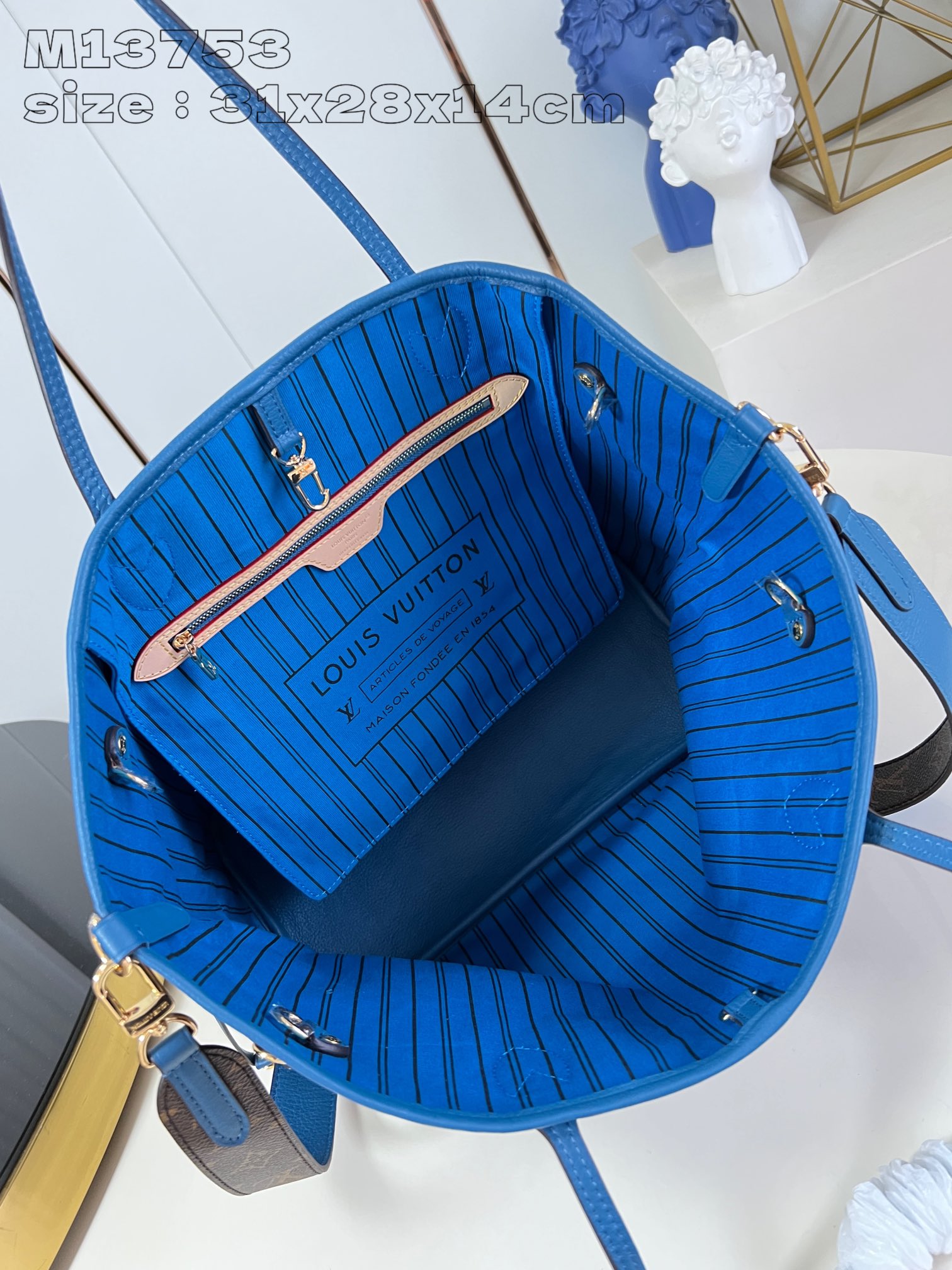 P1200 M13753Blue This reversible Neverfull medium tote bag is made of soft Monogram canvas outlined with cowhide trimmings in a spacious configuration with a colorful fabric lining and two side straps that can be cinched or unfolded for a distinctive look Slim handles for carrying on the shoulder or elbow Detachable zipper pocket can be used as a clutch or as a pocket 31 x 28 x 14 cm (L x H x W)