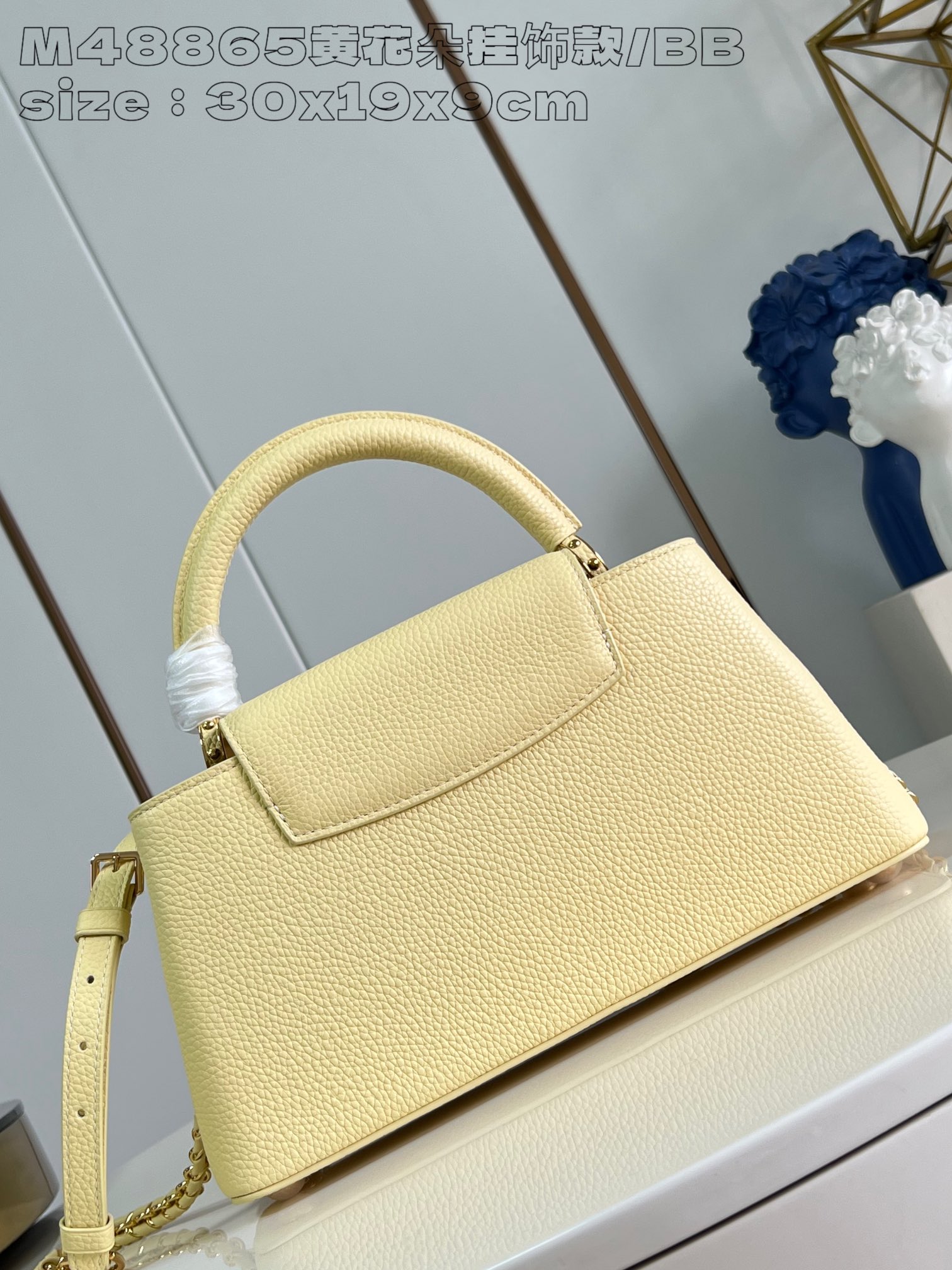 P2400 M48865 Yellow Flower Charm/Small This medium Capucines East-West bag is made from grained cowhide leather that gives a chic luster to metal pieces such as the octagonal chain links. The detachable Arty chain illuminates the long, slender silhouette and the interior features a zippered pocket and a patch pocket. 30 x 19 x 9 cm (L x H x W).