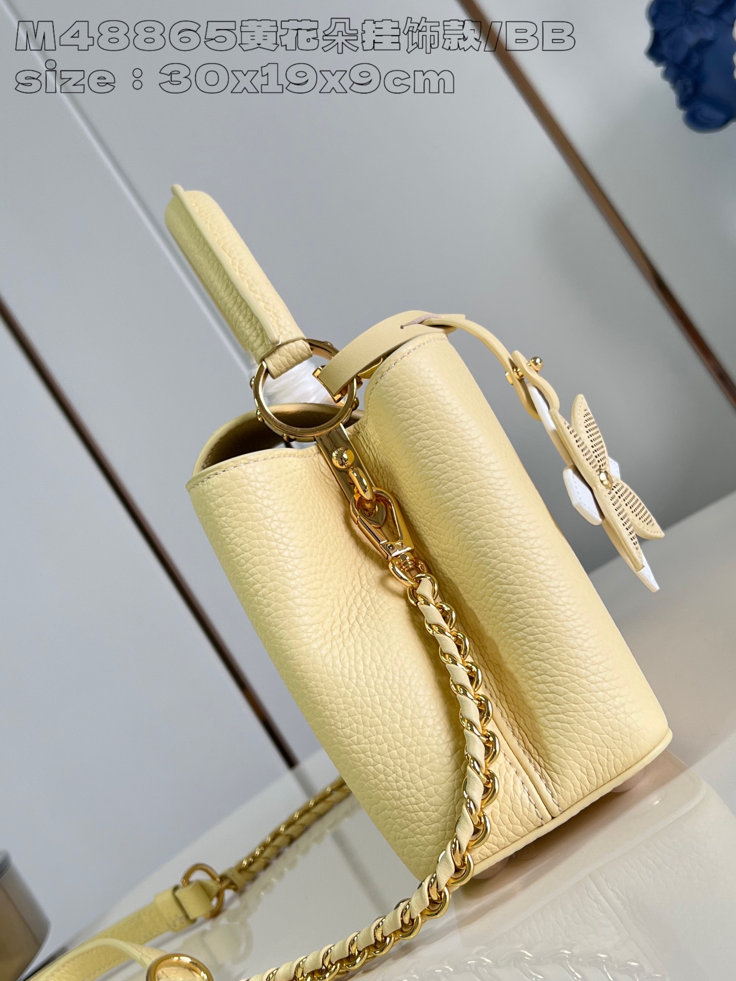 P2400 M48865 Yellow Flower Charm/Small This medium Capucines East-West bag is made from grained cowhide leather that gives a chic luster to metal pieces such as the octagonal chain links. The detachable Arty chain illuminates the long, slender silhouette and the interior features a zippered pocket and a patch pocket. 30 x 19 x 9 cm (L x H x W).