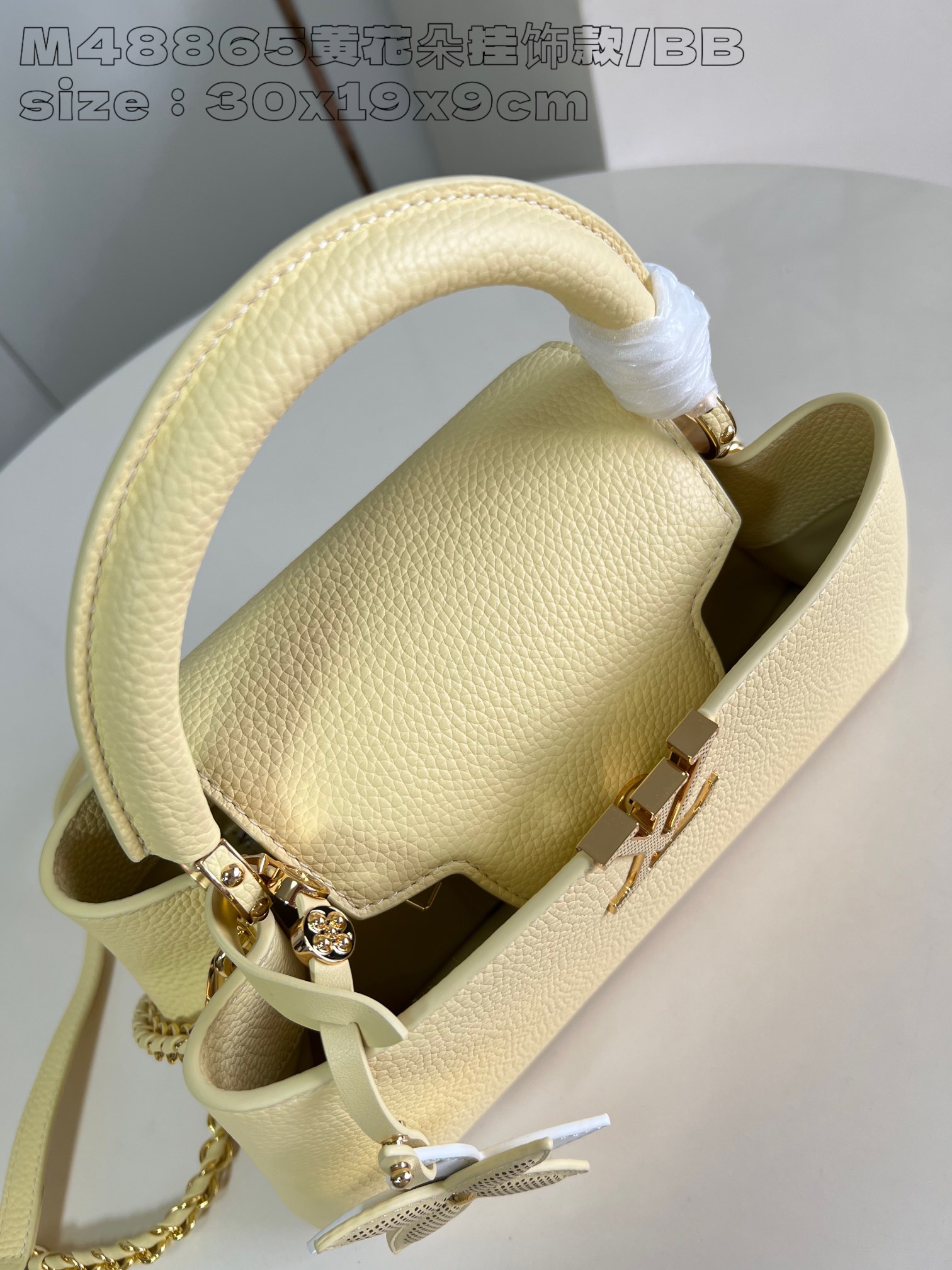 P2400 M48865 Yellow Flower Charm/Small This medium Capucines East-West bag is made from grained cowhide leather that gives a chic luster to metal pieces such as the octagonal chain links. The detachable Arty chain illuminates the long, slender silhouette and the interior features a zippered pocket and a patch pocket. 30 x 19 x 9 cm (L x H x W).