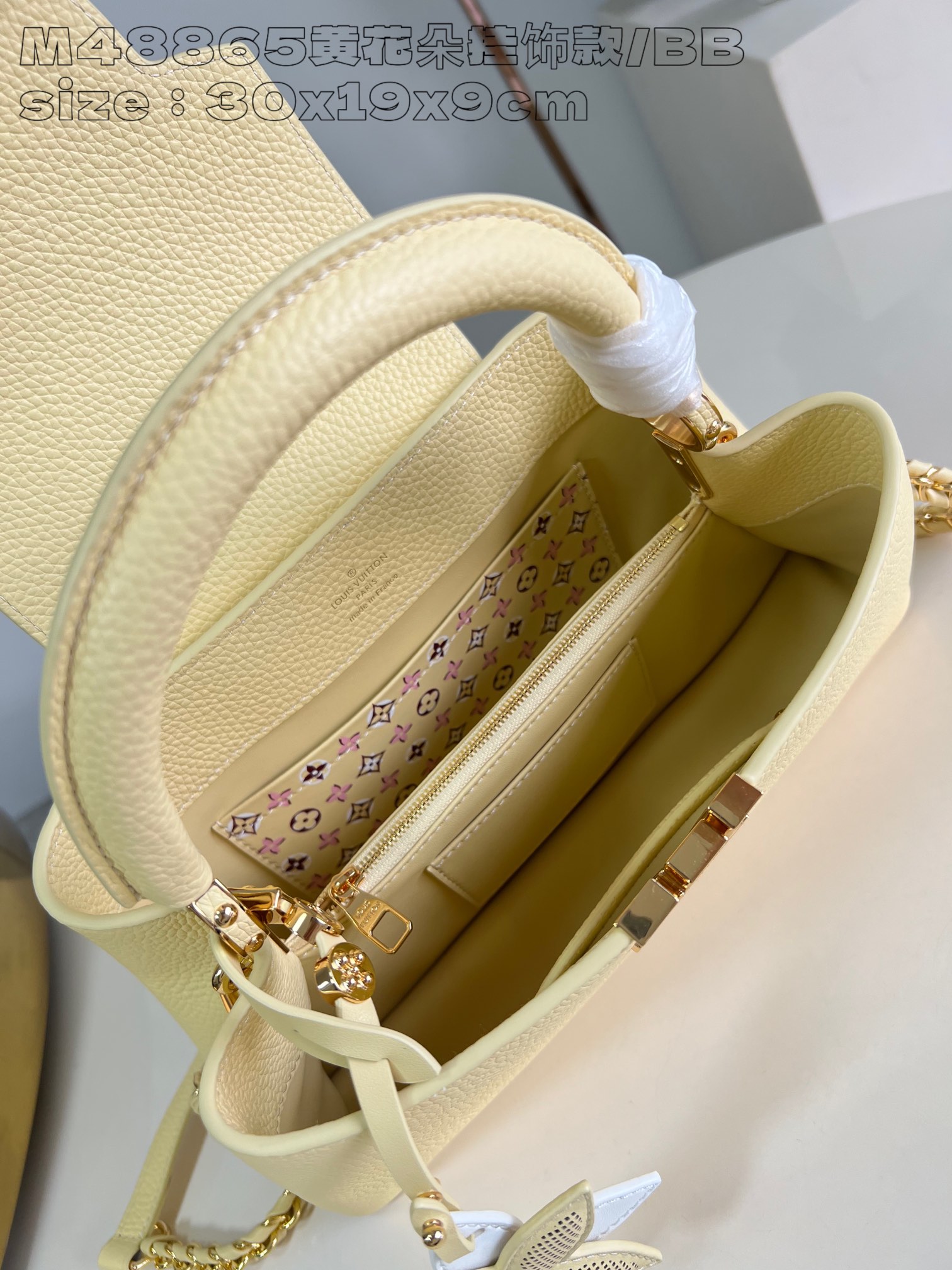 P2400 M48865 Yellow Flower Charm/Small This medium Capucines East-West bag is made from grained cowhide leather that gives a chic luster to metal pieces such as the octagonal chain links. The detachable Arty chain illuminates the long, slender silhouette and the interior features a zippered pocket and a patch pocket. 30 x 19 x 9 cm (L x H x W).