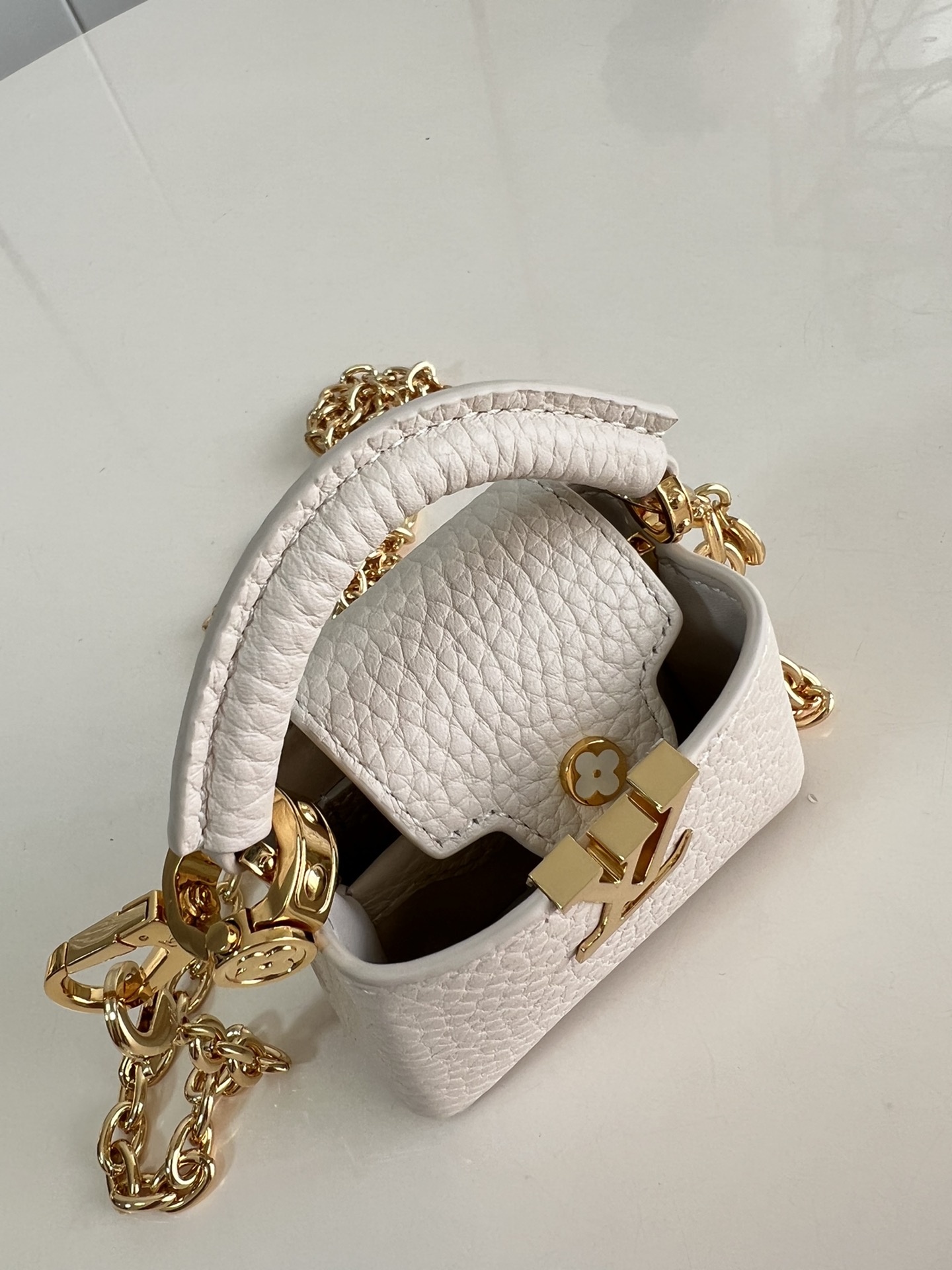 M48865 Super mini Chain Bag M02132 This adorable Micro Bag Capucines is a miniature reinterpretation of the legendary Louis Vuitton handbag design in richly textured cowhide leather with a gold metal LV logo clasp embellished with luxurious logo detailing and a convenient Monogram floral clasp that echoes the design. Ideal for carrying headphones or other small items, it can also be used as a shoulder bag.