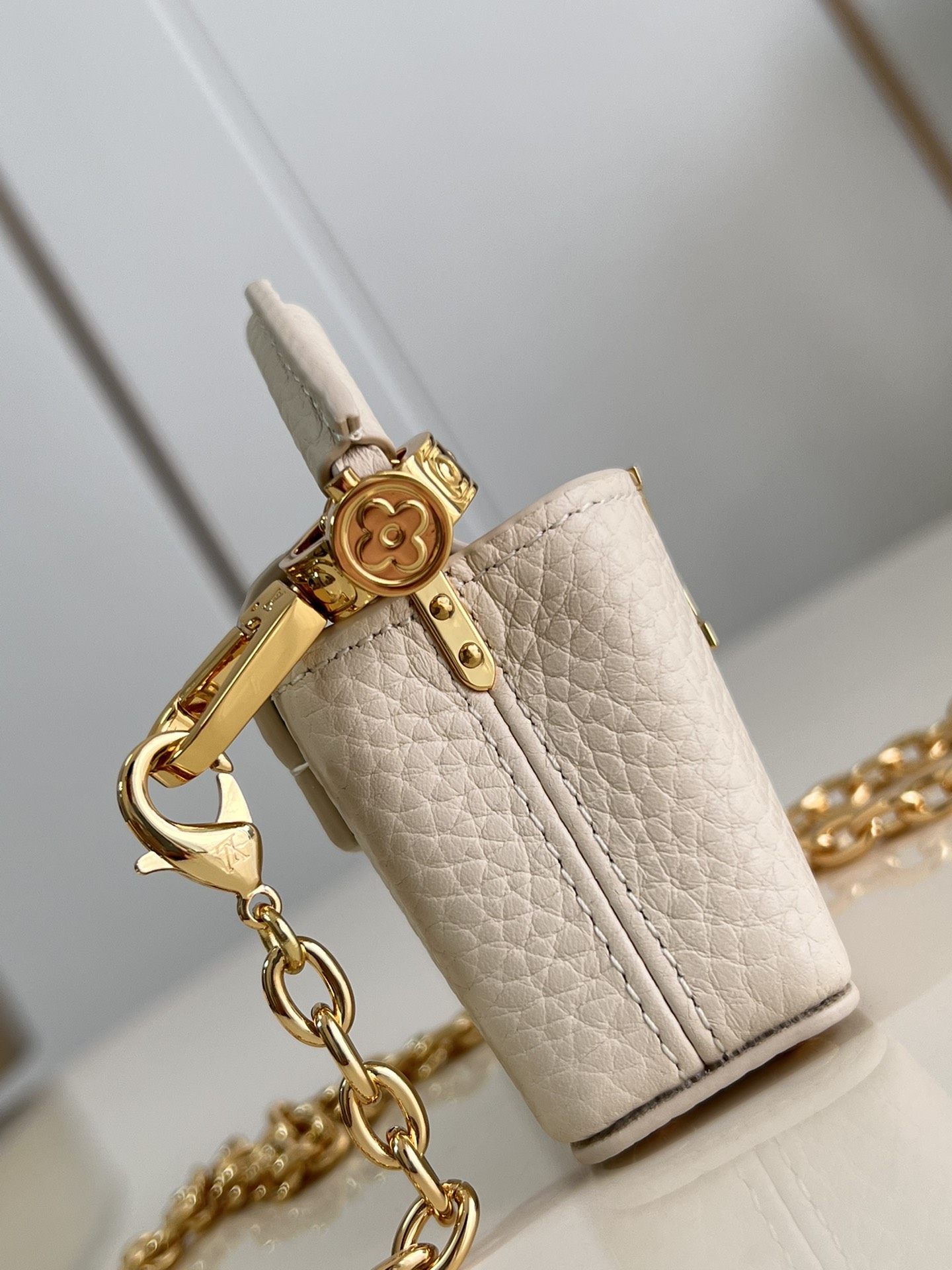 M48865 Super mini Chain Bag M02132 This adorable Micro Bag Capucines is a miniature reinterpretation of the legendary Louis Vuitton handbag design in richly textured cowhide leather with a gold metal LV logo clasp embellished with luxurious logo detailing and a convenient Monogram floral clasp that echoes the design. Ideal for carrying headphones or other small items, it can also be used as a shoulder bag.