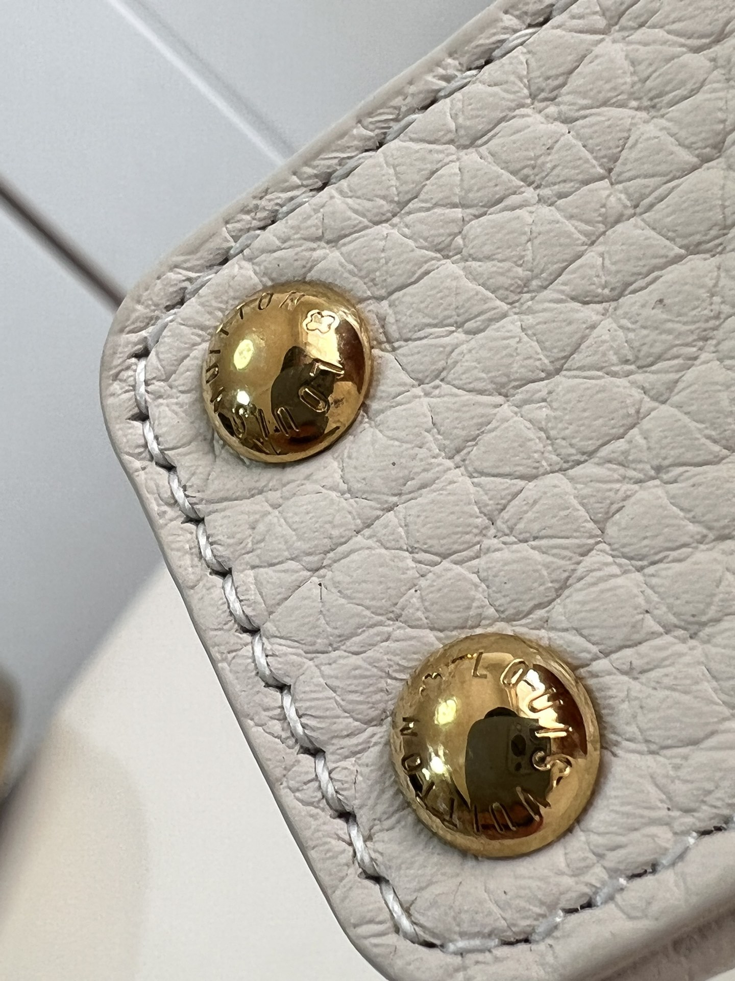 M48865 Super mini Chain Bag M02132 This adorable Micro Bag Capucines is a miniature reinterpretation of the legendary Louis Vuitton handbag design in richly textured cowhide leather with a gold metal LV logo clasp embellished with luxurious logo detailing and a convenient Monogram floral clasp that echoes the design. Ideal for carrying headphones or other small items, it can also be used as a shoulder bag.