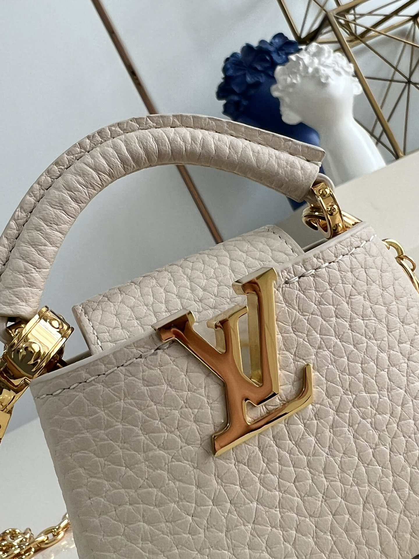 M48865 Super mini Chain Bag M02132 This adorable Micro Bag Capucines is a miniature reinterpretation of the legendary Louis Vuitton handbag design in richly textured cowhide leather with a gold metal LV logo clasp embellished with luxurious logo detailing and a convenient Monogram floral clasp that echoes the design. Ideal for carrying headphones or other small items, it can also be used as a shoulder bag.