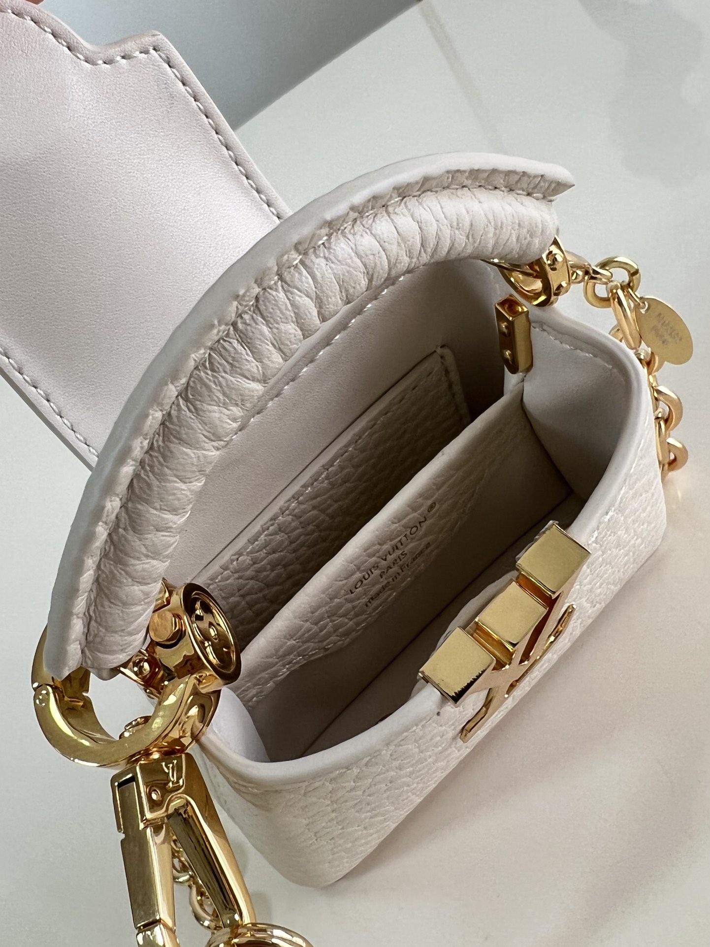 M48865 Super mini Chain Bag M02132 This adorable Micro Bag Capucines is a miniature reinterpretation of the legendary Louis Vuitton handbag design in richly textured cowhide leather with a gold metal LV logo clasp embellished with luxurious logo detailing and a convenient Monogram floral clasp that echoes the design. Ideal for carrying headphones or other small items, it can also be used as a shoulder bag.