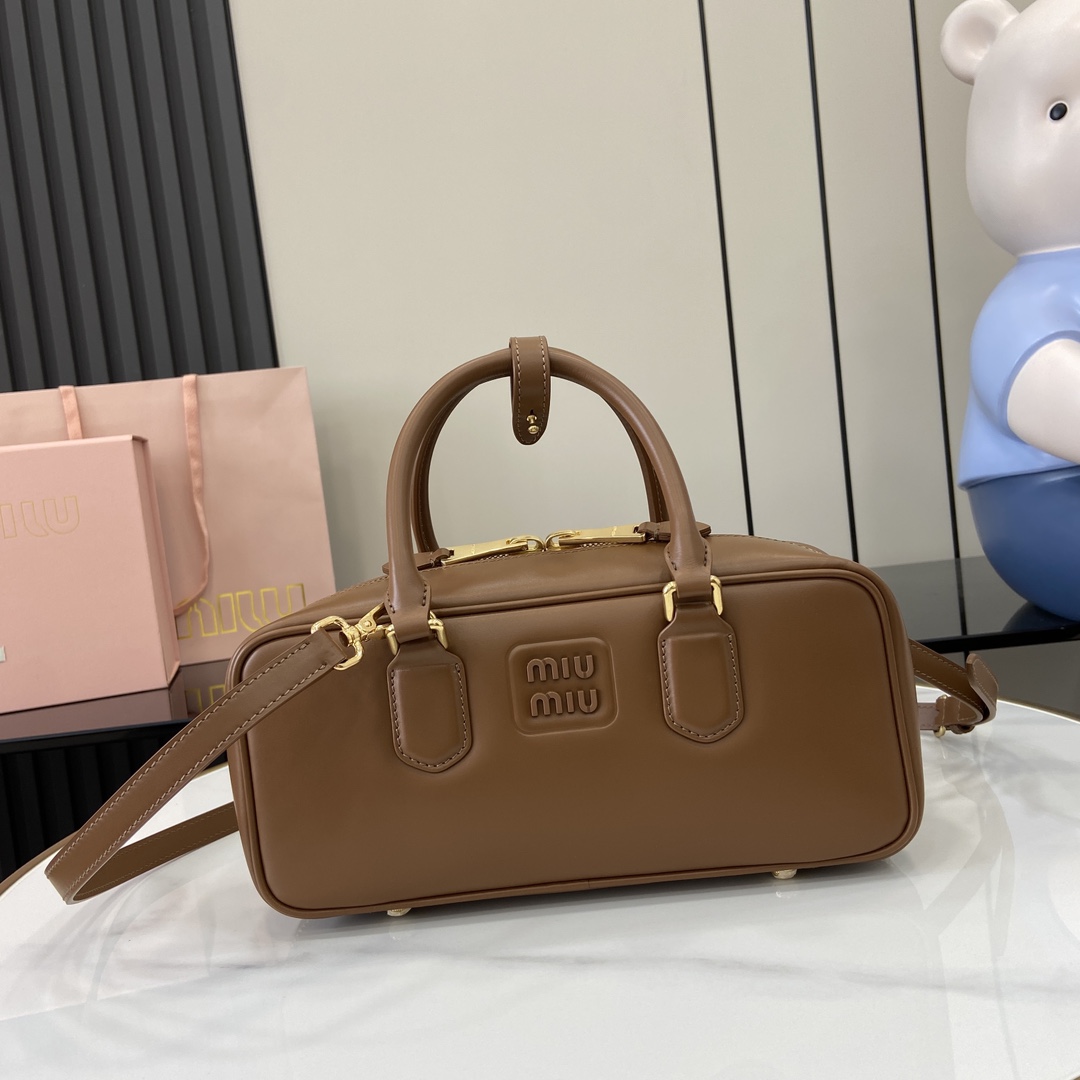 p1720 miumiu缪缪Arcadie 牛皮革中号(27cm)保龄球手提包/斜挎包～干邑色牛皮
这款Arcadic手袋彰显独特的理念即时装是对现实的反映转译为物质形态的工具与金属五金配件的饰面相辉映的字母徽标精致做工卓尔不凡彰显极具辨识度的经典格调动感优雅线条搭配可调式可拆卸肩带呈现富有现代魅力的实用百搭设计
可拆卸可调式肩带
拉链开合
正面涂漆金属字母徽标
带衬里配拉链口袋
配脚钉
型号：5BB148
尺寸：27（长）x 12（宽）x 9cm（厚）
颜色：棕色/-高仿包包