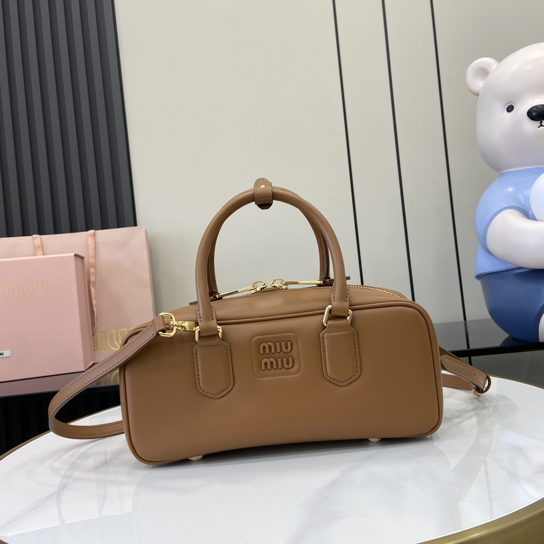 p1720 miumiu缪缪Arcadie 牛皮革中号(27cm)保龄球手提包/斜挎包～干邑色牛皮
这款Arcadic手袋彰显独特的理念即时装是对现实的反映转译为物质形态的工具与金属五金配件的饰面相辉映的字母徽标精致做工卓尔不凡彰显极具辨识度的经典格调动感优雅线条搭配可调式可拆卸肩带呈现富有现代魅力的实用百搭设计
可拆卸可调式肩带
拉链开合
正面涂漆金属字母徽标
带衬里配拉链口袋
配脚钉
型号：5BB148
尺寸：27（长）x 12（宽）x 9cm（厚）
颜色：浅棕全皮/-高仿包包