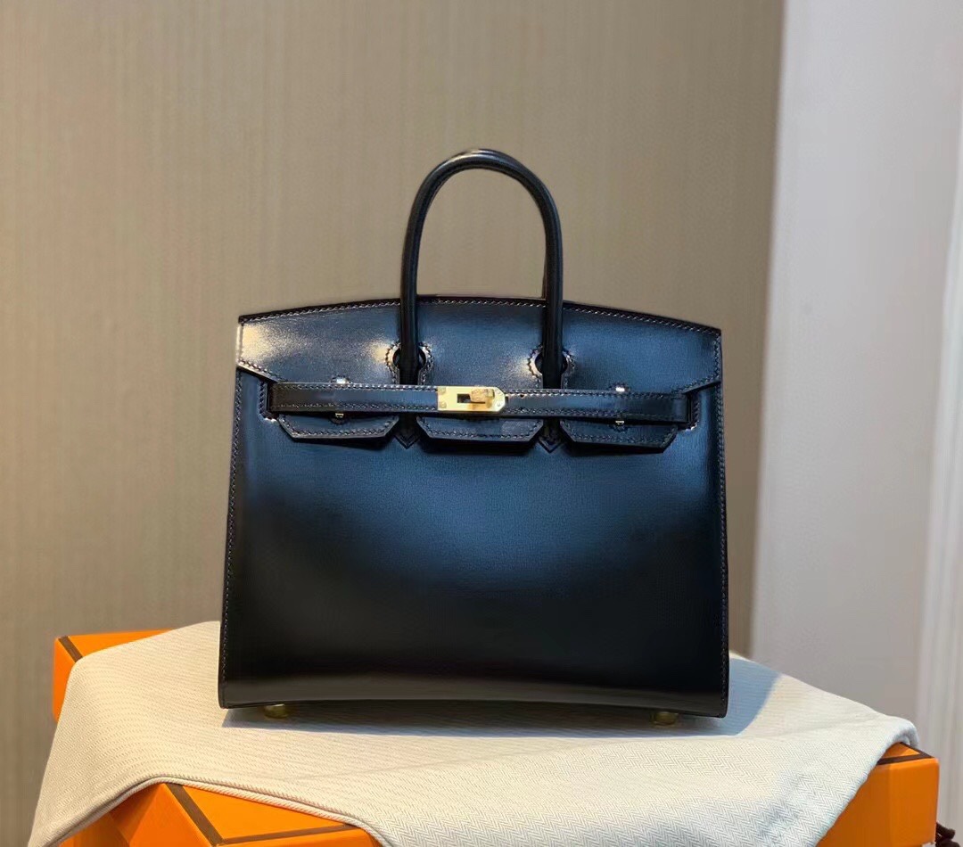 Birkin 25 sellier Box 皮 黑金～
𝗕𝗼𝘅 𝗖𝗮𝗹𝗳皮 属细纹小牛皮肉面组织紧密皮料毛孔粒面小且清晰有竖状纹也叫牙签纹是普皮档次中较高的品种制作工艺难度堪比鳄鱼皮！因此皮种特性娇贵极不耐刮蹭但高级感满满～-高仿包包